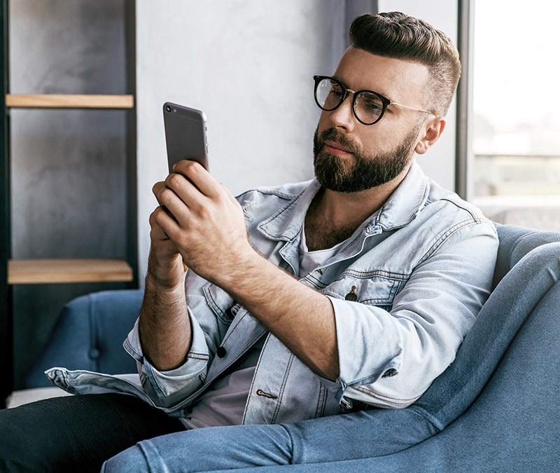 Un homme de la génération Z ou un millénial qui utilise son smartphone en toute décontraction, incarnant le comportement numérique des millennials.
