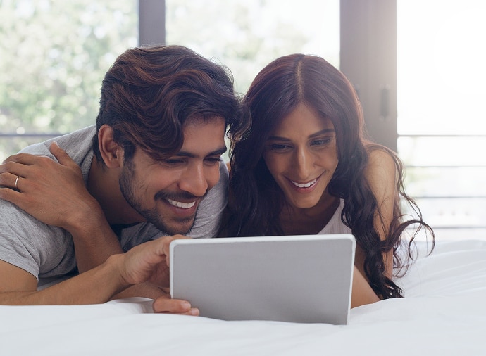 Un homme et une femme riant en regardant une tablette